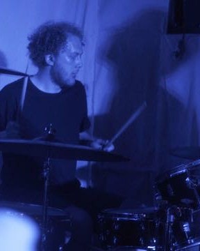 Jack drumming at a gig under blue light