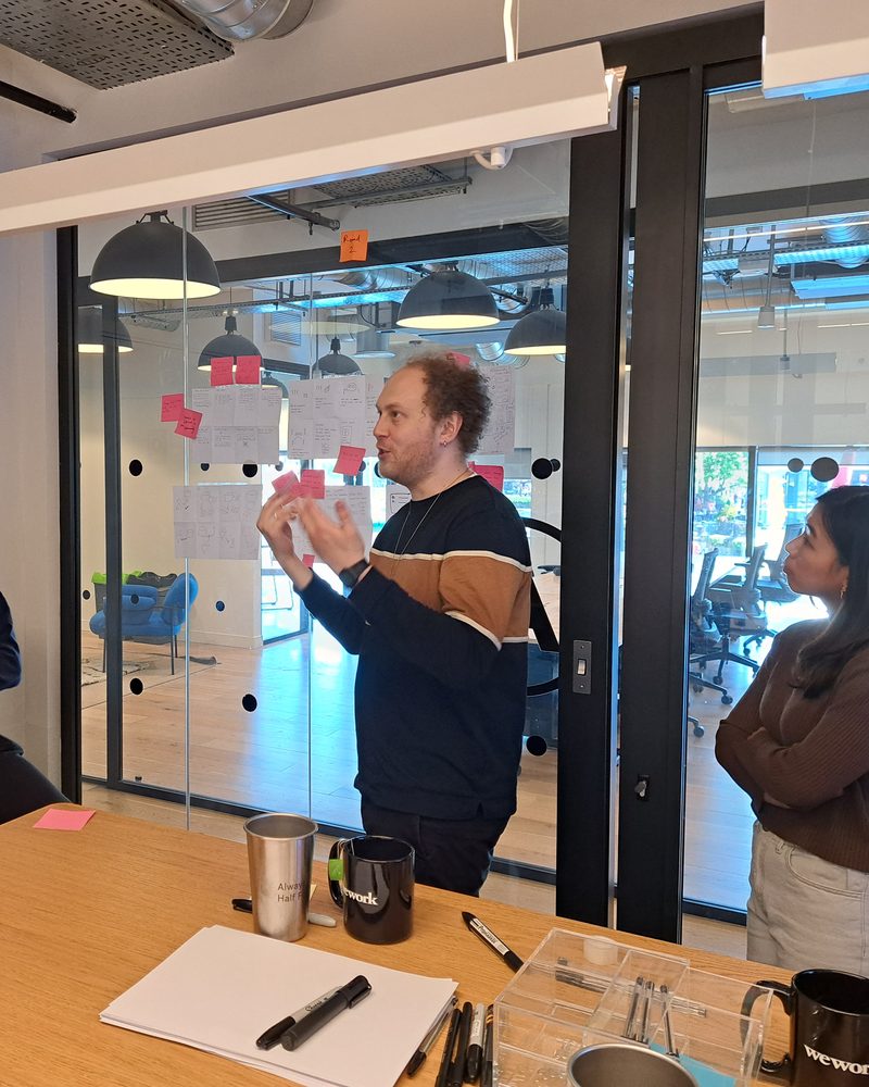 Jack running a design workshop, sketches and sticky notes on the glass